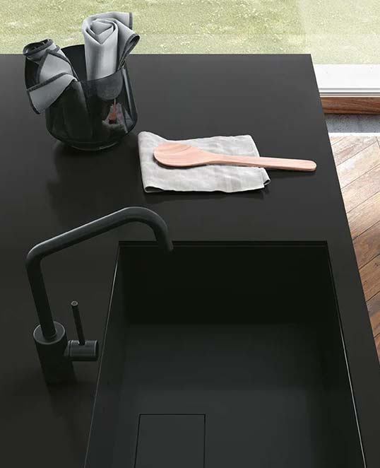 Effet résine XXL pour surfaces contemporaines sobres et élégantes Dalles céramiques XXL effet résine sur plan de travail sombre avec surface mate continue et esthétique contemporaine épurée