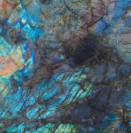 Lecture minérale et reflets selon l’éclairage Gros plan de céramique effet labradorescence, veines minérales et reflets bleus changeants selon la lumière