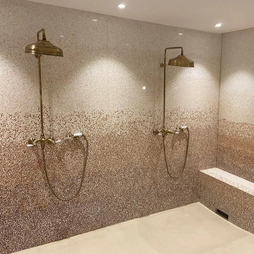 Douche et murs revêtus de terrazzo minéral beige créant une ambiance chaleureuse et durable
